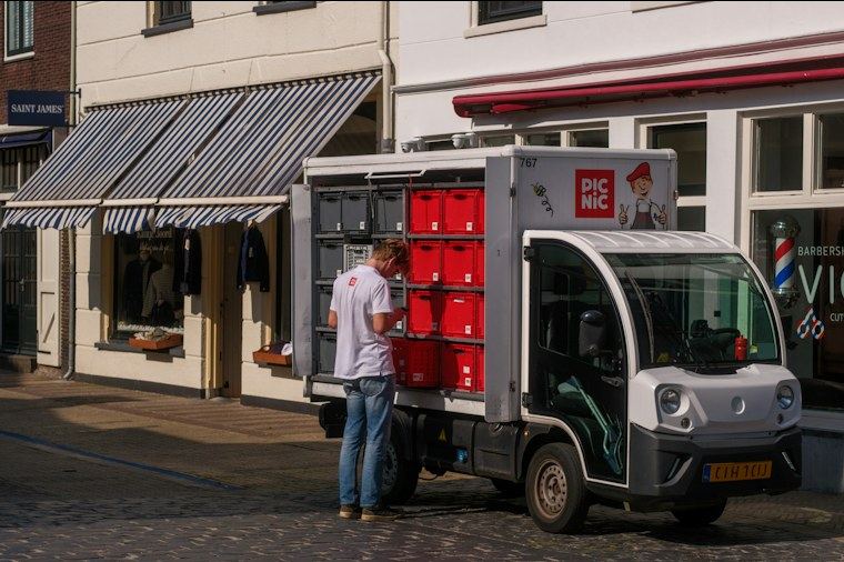 Entregador carregando caixas em um caminhão parado em frente ao comércio