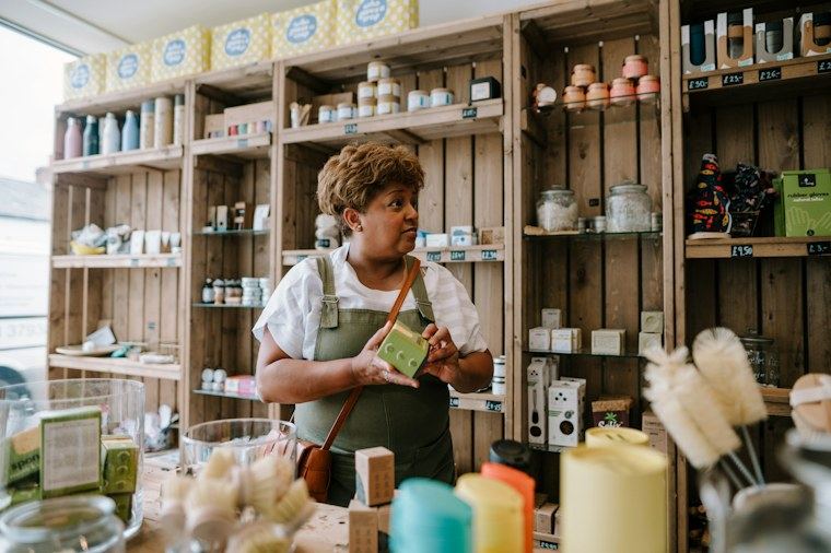 Lojista organizando produtos nas prateleiras de madeira da loja